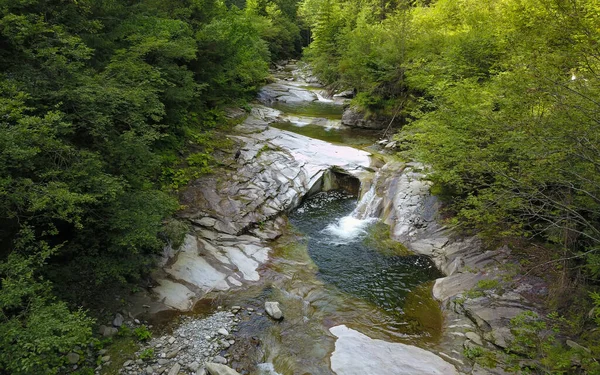 Bir dağ nehri oluşumunun insansız hava aracı fotoğrafı aşınmış büyük taş parçalarından akarken basamaklı çağlayanlar ve göletler oluşturuyor. Latorita Dağları, Karpatya, Romanya.
