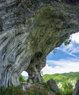 Karpat Dağları 'nın içindeki vadilerle kayalık bir kanyonun üzerindeki görüş açısı. Bir dağın tepesindeki uçurumda bir atari salonu aşınmıştı. Calcareous oluşumu Oltetului Vadisi 'nde.. 