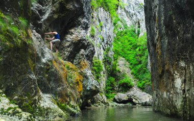 Kayalık bir kanyonda, hızlı bir nehrin üzerinde yürüyüş yapan biri. Kişi, aşınmış kayalıklarda oyulmuş patikaya tutunur. Ramet vadilerini, Karpatya 'yı, Romanya' yı keşfediyor.