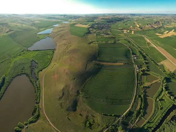 Çiftliklerin ve tarım alanlarının ortasındaki göl, gölet ve bataklık alanlarından oluşan doğal bir rezervasyonun üzerindeki hava aracı görüntüsü. Mandra Rezervasyon Transilvanya, Romanya.