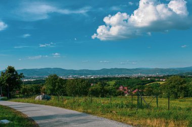 Köy yolu köy üzerinde kırsal ve kentsel yerleşimcilerin manzarasıyla esiyor.