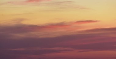 Canlı, sihirli renkler ve yumuşak akşam ışığında süzülen tuhaf bulutlarla dolu rüya gibi bir gün batımı.