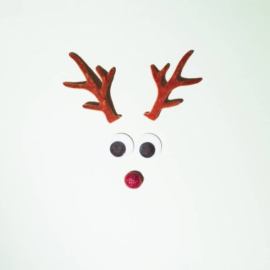 Geyik boynuzları beyaz bir zemine yerleştirilmiş. Kış durgun konsepti. Yeni yıl seti ve kırmızı burun süslemesi..