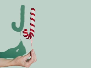 El bir Noel süsü tutuyor ve gölge bize yanındaki boşlukta sözcüğe devam etmemiz için büyük bir 