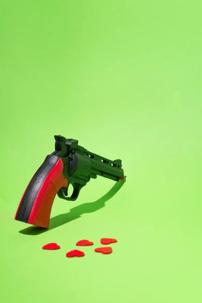 Revolver Green Background Red Hearts Scattered Floor Conceptual Setting Murder — Stock Fotó