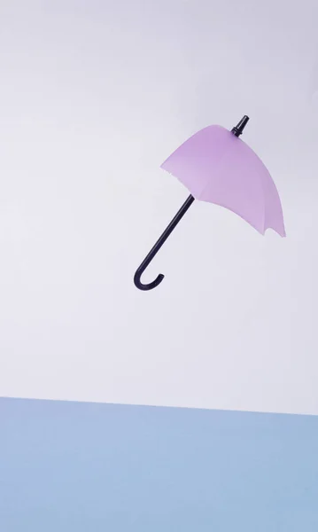 Broken purple umbrella in the wind. Two-tone background in shades of blue. Minimalism.