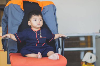 Asian children wearing traditional Thai costumes and sitting on chairs at Sukhothai, Thailand.