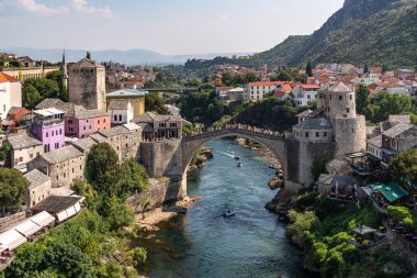 This photo captures a river running through Mostar city, with a prominent Old Bridge in the background, Bosnia and Herzegovina