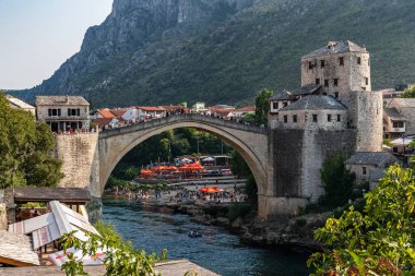 This photo captures a river running through Mostar city, with a prominent Old Bridge in the background, Bosnia and Herzegovina