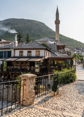 Mostar, Bosna-Hersek, Ağustos 2023. Mostar 'ın arka planında muhteşem bir minaresi olan muhteşem bir kaldırım taşı caddesinin büyüleyici manzarası..