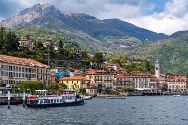 Menaggio, İtalya, Nisan. 24, 2024. Como Gölü 'ne bir feribot yanaştı. Su sakin ve gökyüzü parçalı bulutlu..