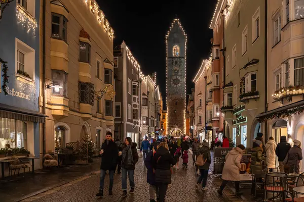 Vipiteno, Alto-Adige, İtalya, Aralık 2023. Turistlerle dolu büyüleyici Vipiteno kasabası Noel ışıklarıyla süslenmiş kaldırım taşı caddesi boyunca toplandı