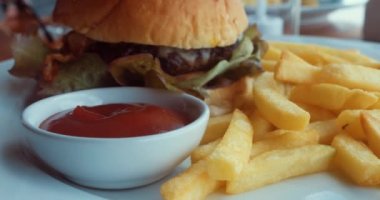 Lezzetli burger ve ketçaplı patates kızartması ile yakın çekim tabağı. Amerikan yemeği. Yüksek kalite 4k görüntü