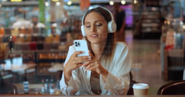 Γοητευτική Καυκάσια Γυναίκα Ακουστικά Που Χρησιμοποιεί Smartphone Ενώ Χαλαρώνει Μια — Αρχείο Βίντεο