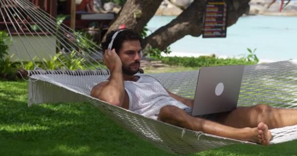 Rahatlamış Genç Adam Dizüstü Bilgisayarı Açar Sahildeki Hamakta Yeni Bir — Stok video