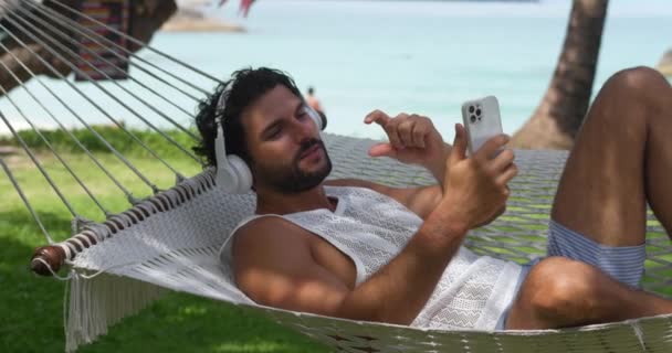 Tatilde Yakışıklı Kulaklık Takan Online Toplantı Yapan Hamakta Dinlenirken Video — Stok video