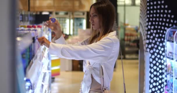 Młoda Kobieta Wybiera Antyperspirant Supermarkecie Wyczuwa Zapach Pokazując Dezodorant Twarzy — Wideo stockowe