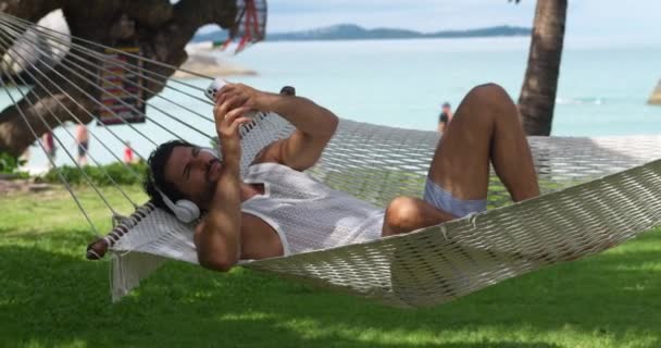 Erkek Turist Kulaklık Takıyor Hamakta Dinleniyor Telefon Kullanıyor Web Sitelerine — Stok video