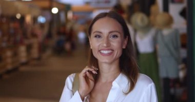 Alışveriş merkezinde bir kadının portresi, kenarlara bakıyor ve güzel dişli bir gülümsemeye yayılıyor kameraya bakıyor.