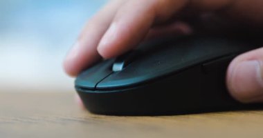 Yakın plan. Bir adam bilgisayar faresine tıklıyor ve bilgisayar başında çalışırken silindir kullanıyor. İnternet 'te bilgi aranıyor