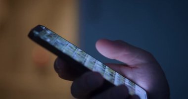 Yakın plan: erkek eli, gece evde masada akıllı telefon kullanıyor. Yüksek kalite 4k görüntü