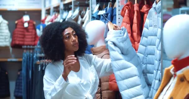 상점에서 물건을 컬렉션에서 재킷을 입으려고 아프리카 미국인 — 비디오