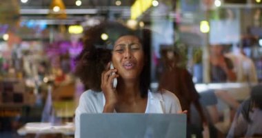 Afrikalı Amerikalı endişeli kadın cep telefonuyla konuşuyor, dizüstü bilgisayarda oturuyor, hayal kırıklığını ve umutsuzluğu dile getiriyor.