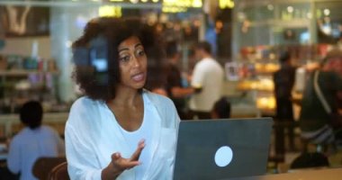 Çok ırklı, afro saçlı, laptopun başında oturmuş video görüşmeleri yapan çok yönlü bir kadın. Uzaktaki internet iletişimi. Video konferansı. Çevrimiçi sohbet kavramı.
