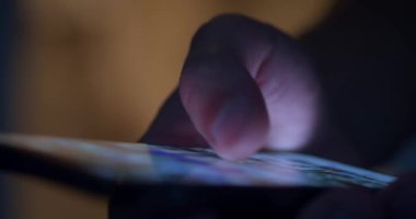 Yakın plan: erkek eli, gece evde masada akıllı telefon kullanıyor. Yüksek kalite 4k görüntü