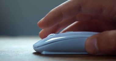 Male freelancer click white computer mouse and scroll internet websites online searching business information on work desk. Close up of male hand using computer mouse to working at laptop