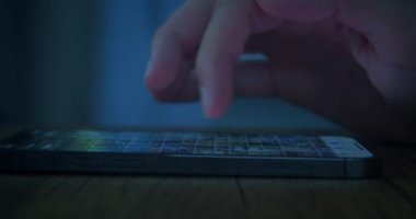 Yakın plan: erkek eli, gece evde masada akıllı telefon kullanıyor. Yüksek kalite 4k görüntü
