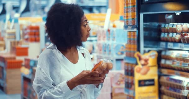 多种族的深色皮肤女人 在购买食品时 用有机动物蛋阅读包装上的标签 — 图库视频影像
