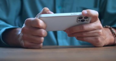 Angry man looks at the smartphone screen and fights with his fist at the table. Close-up of a man losing his temper due to a non-working application on a smartphone and showing rage while feeling