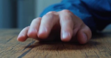 Male waiting for something while fingers tap on the table. Close up male hand nervously tapping finger on the table.