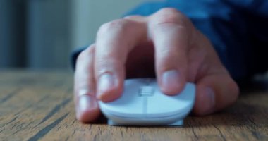 Mans hand actively uses a computer mouse while working at a computer, clicks and scrolls online web pages, close-up macro shooting.