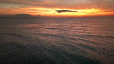Flight over water forward to the fascinating landscape of sunset and beautiful sea at evening time. Golden sunset reflected on the sea surface. Cinematic aerial drone video the time after sunset over