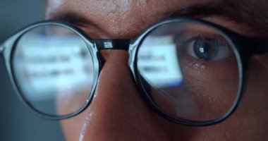 Computer Screen Reflection On Eyeglasses of man internet user surfing the net at night time. Close up mans eyes in eyeglasses scroll internet websites, monitor screen reflect searching images.