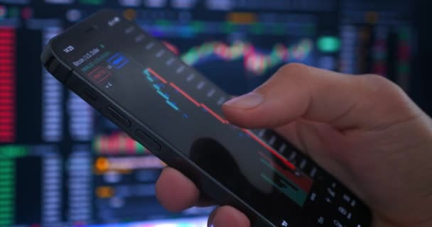 男性の手のクローズアッププロのトレーダーブローカーは 株式取引所での暗号化株式市場の成長のグラフをスマートフォンを保有し 分析しています — ストック動画