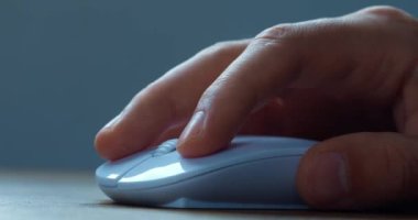 Close up hand of office worker actively using a computer mouse while working in the office. The male employee hand uses the mouse to work at the computer. White computer mouse, close-up macro.