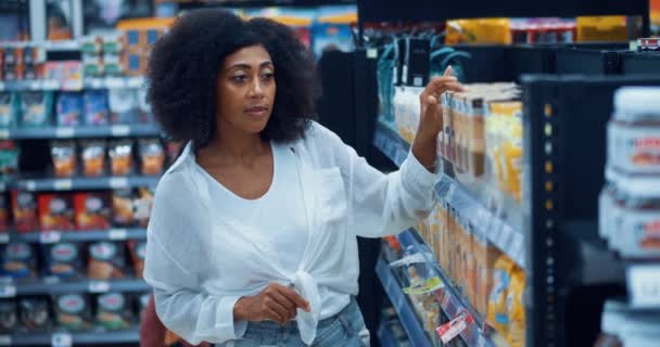 アフリカ系アメリカ人女性はラベルを読み スーパーマーケットの食料品部門でシリアルを購入しながら価格をチェック — ストック動画