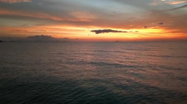 Cinematic shot of time after sunset over the sea. A beautiful golden-orange sunset sky reflected in the sea water. The beauty of mother earth. Aerial view, the drone camera moves away