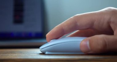 Close up male hand uses white computer mouse, click and scroll the mouse roller, searching for information on the Internet, surfing web pages. Working at computer using handheld pointing device.