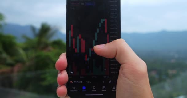 Close Crypto Enthusiast Holding Mobile Phone App Studying Graph Changes — Vídeo de Stock