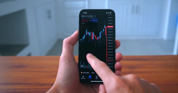 Male Trader Holds Smart Phone Analyzes Crypto Stock Market Purchase — Video