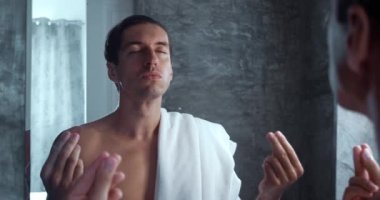 Calm young male meditate in bath in front of mirror in the morning before the start of the day. Millennial male tries to calm down with meditation in the bath, looking at himself in the mirror.