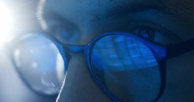 Gözlüklü erkek gözlerini kapat. Geceleri bilgisayar başında çalışan bilgisayar korsanı. İkili program kodu gözlüklere yansıyor. Gece vakti gözlük hackleme sitesindeki hackerların gözleri. Siber Suçlar.