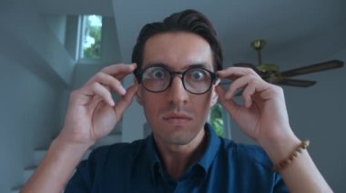 Scared man takes off his glasses and is frightened by what he sees. Portrait of scared young 30 millennial man. Business man takes off glasses in fright and covers his mouth, scared by bad news.