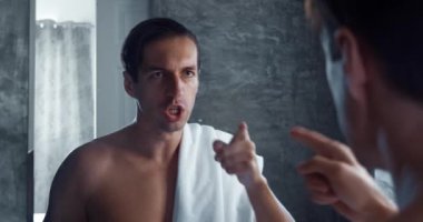 A person confidently motivates himself to overcome difficulties by standing in front of the mirror in bathroom in the morning. male in bath talking to himself, motivating himself for new day.