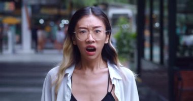 Scared young asian female takes off glasses and look confused at the camera. Portrait confused asian woman in glasses 20 years old scared by what she saw. Concert person suddenly scared and confused.