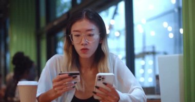 Young asian woman buying online with credit card and smartphone. Woman using smartphone and shopping online at cafe. Concept of online shopping by mobile technology and modern lifestyle.